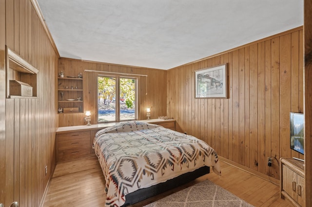 bedroom with wood walls, light wood finished floors, and baseboards