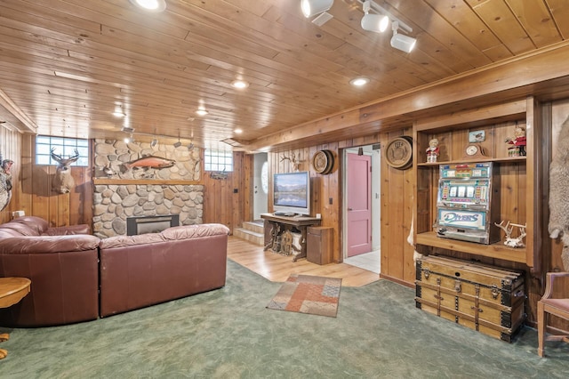 living room featuring wood ceiling, wood walls, plenty of natural light, a stone fireplace, and wood finished floors