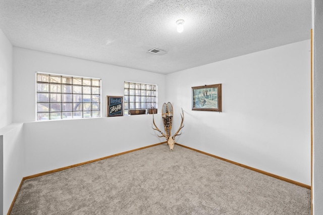carpeted spare room with a textured ceiling and baseboards