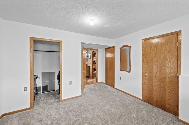 unfurnished bedroom featuring a spacious closet, carpet floors, a closet, baseboards, and a textured ceiling