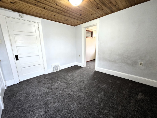 carpeted spare room featuring wood ceiling