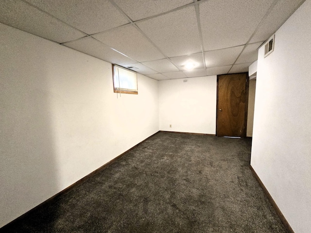 basement with a drop ceiling and dark colored carpet