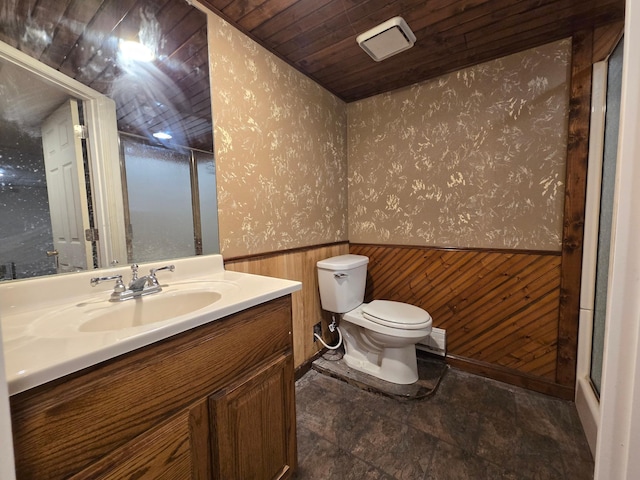 bathroom with toilet, wood ceiling, wood walls, and vanity