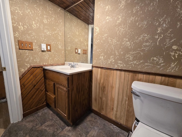 bathroom with toilet, vanity, wood ceiling, and wooden walls