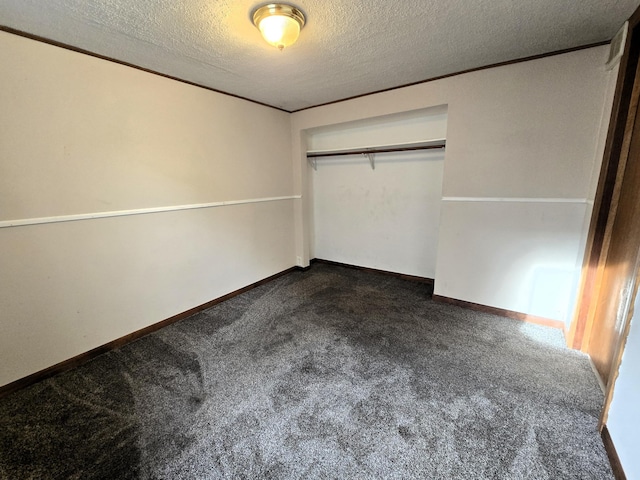 unfurnished bedroom with a textured ceiling, a closet, and dark carpet