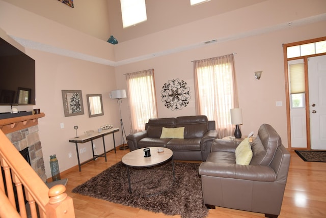 living room featuring a high ceiling, a fireplace, and light hardwood / wood-style flooring