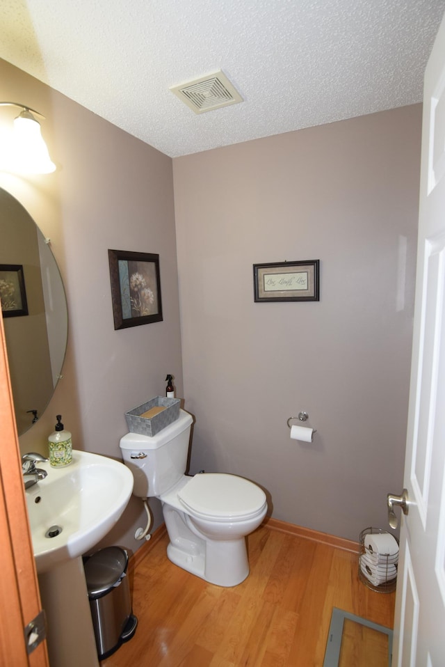 bathroom featuring a textured ceiling, hardwood / wood-style floors, sink, and toilet