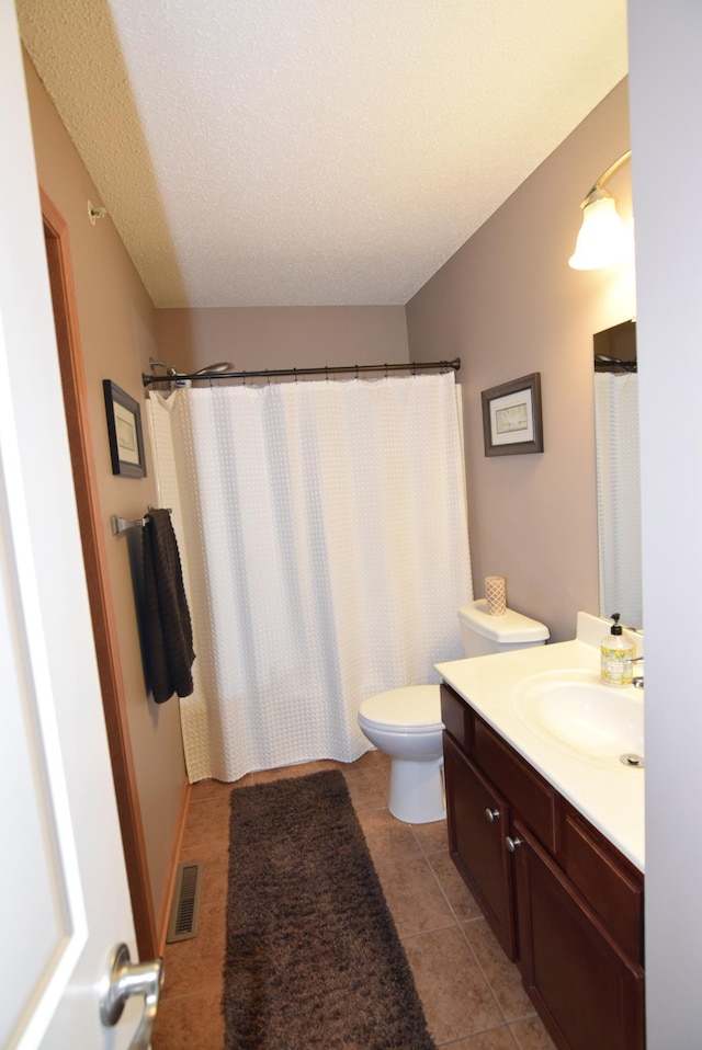 bathroom featuring toilet, walk in shower, tile patterned floors, vanity, and a textured ceiling