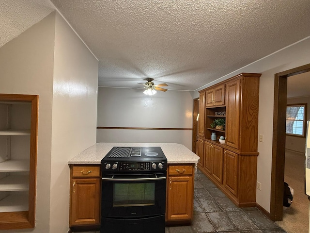 kitchen featuring black / electric stove, brown cabinetry, a ceiling fan, and a peninsula