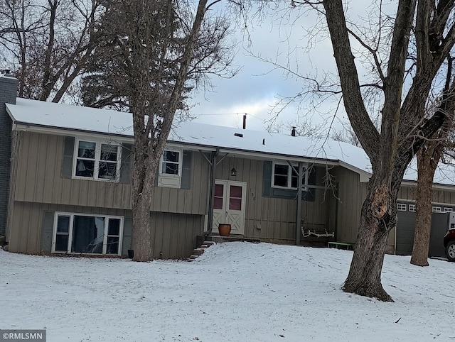 snow covered property with a garage