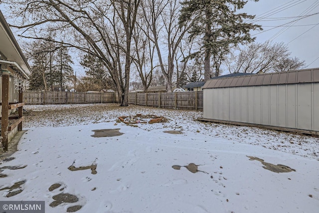 yard layered in snow featuring a shed