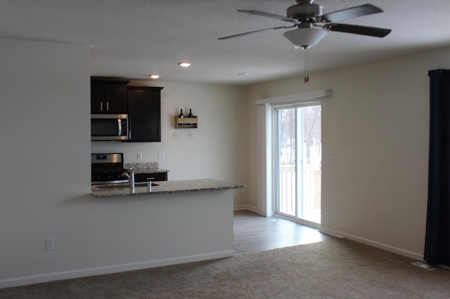 kitchen featuring light carpet, stainless steel appliances, sink, ceiling fan, and light stone counters