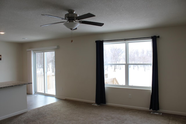 unfurnished room with ceiling fan, light colored carpet, and a textured ceiling