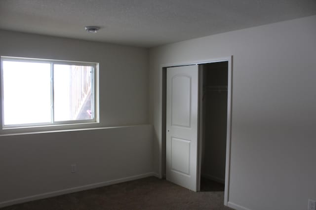 unfurnished bedroom featuring dark carpet and a closet