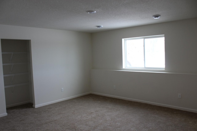 unfurnished room with carpet and a textured ceiling