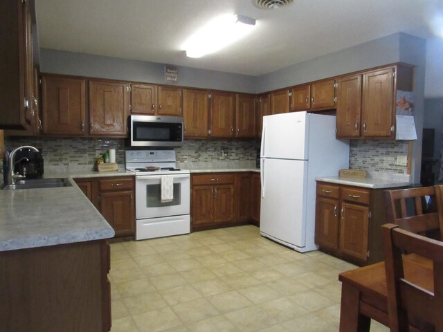 kitchen with tasteful backsplash, sink, and white appliances