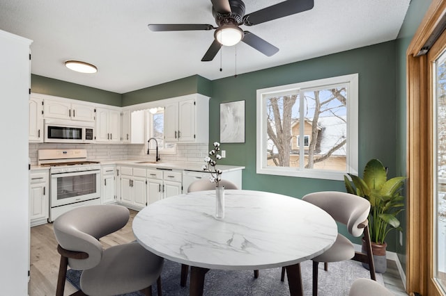 kitchen featuring sink, white cabinetry, white appliances, and tasteful backsplash