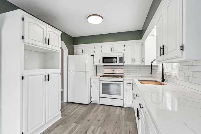 kitchen with sink, white appliances, white cabinetry, and decorative backsplash