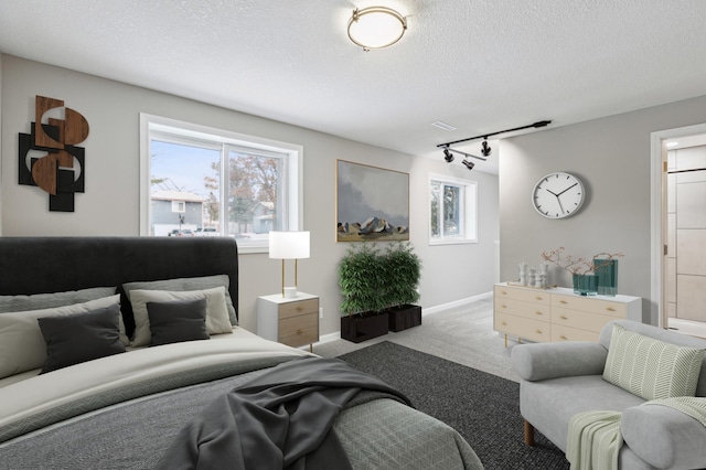 carpeted living room featuring a textured ceiling and track lighting