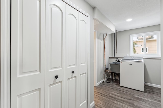 clothes washing area with sink, washer / dryer, light hardwood / wood-style flooring, and a textured ceiling