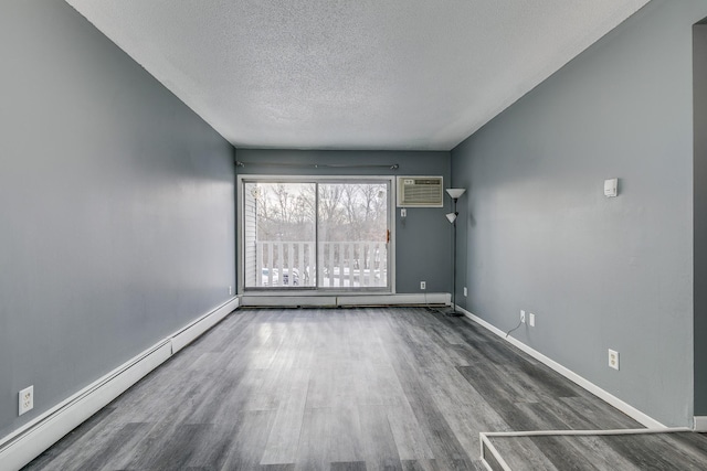 empty room with baseboards, a wall unit AC, baseboard heating, and wood finished floors