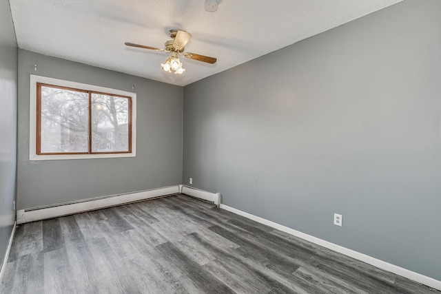 spare room with ceiling fan, a textured ceiling, a baseboard heating unit, baseboards, and dark wood-style floors