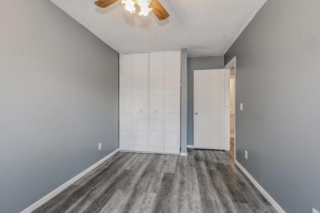 unfurnished bedroom featuring dark wood-style floors, a closet, baseboards, and a textured ceiling