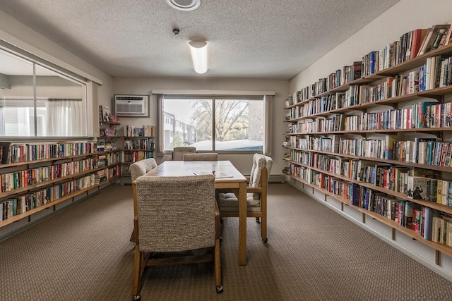 interior space featuring bookshelves, dark colored carpet, and an AC wall unit