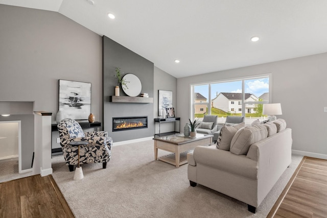 living room featuring vaulted ceiling, a large fireplace, and light wood-type flooring