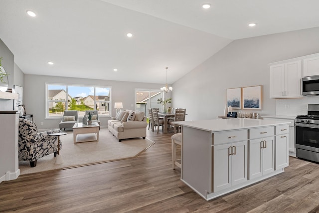 kitchen with a notable chandelier, a center island, white cabinetry, light wood-type flooring, and stainless steel appliances