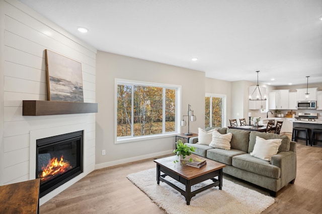 living room with a large fireplace, sink, and light hardwood / wood-style flooring