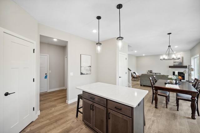 kitchen featuring dark brown cabinetry, hanging light fixtures, a center island, and light wood-type flooring