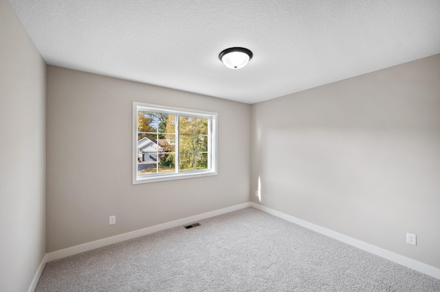 spare room featuring carpet flooring and a textured ceiling