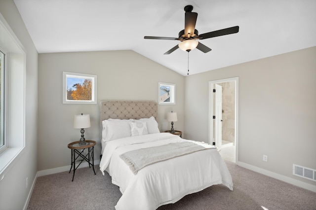 bedroom with vaulted ceiling, light colored carpet, ceiling fan, and ensuite bath