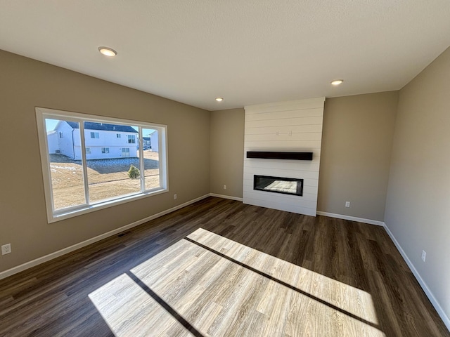 unfurnished living room with a large fireplace and dark hardwood / wood-style floors