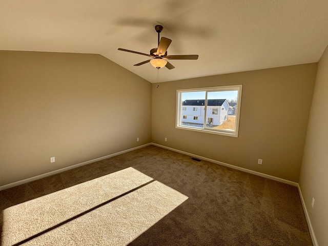 spare room with ceiling fan, lofted ceiling, and dark carpet