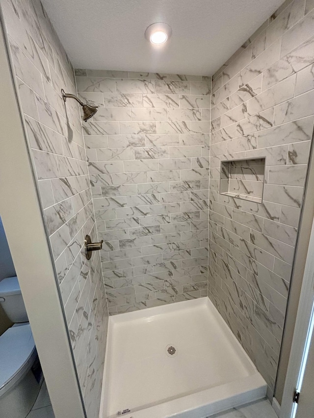 bathroom with tiled shower and toilet