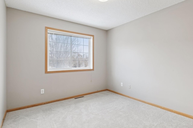 unfurnished room featuring a textured ceiling and light colored carpet