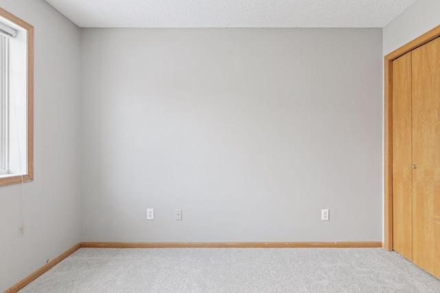 unfurnished bedroom with light colored carpet and a textured ceiling