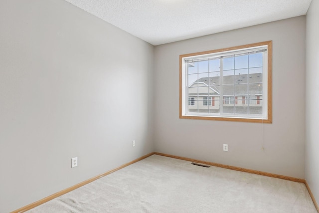 carpeted empty room with a textured ceiling