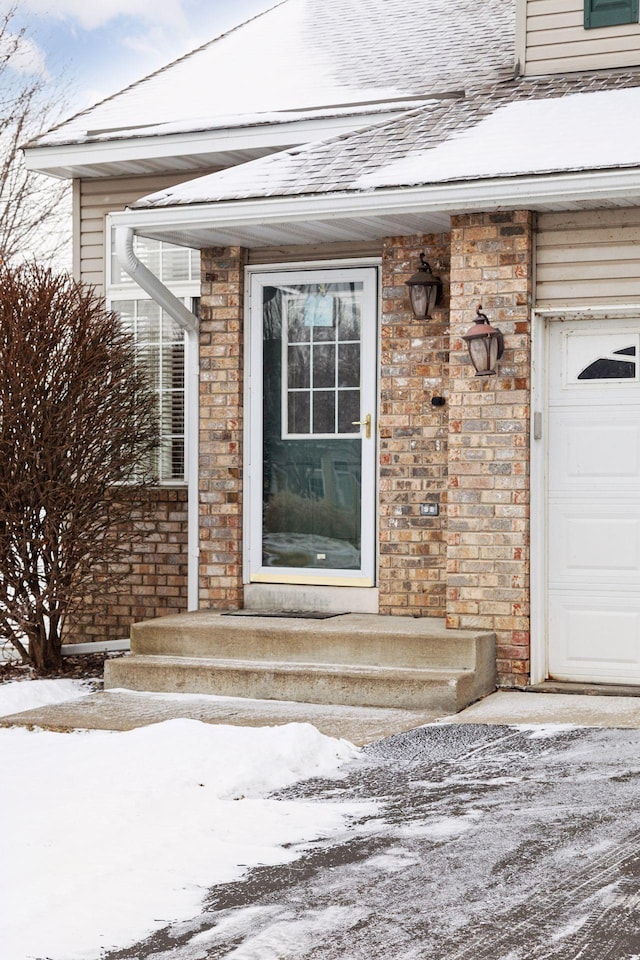 snow covered property entrance featuring a garage