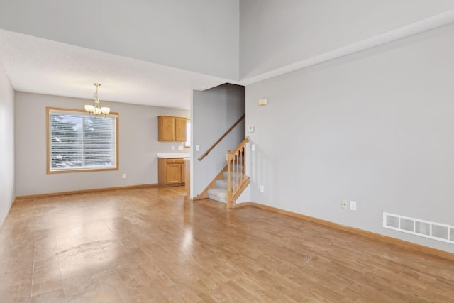 unfurnished living room with an inviting chandelier and light wood-type flooring