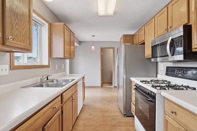 kitchen with white appliances, light hardwood / wood-style floors, a textured ceiling, sink, and pendant lighting