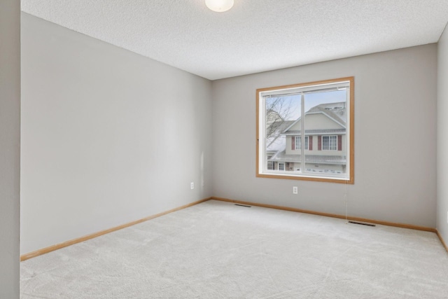 spare room featuring a textured ceiling and light colored carpet