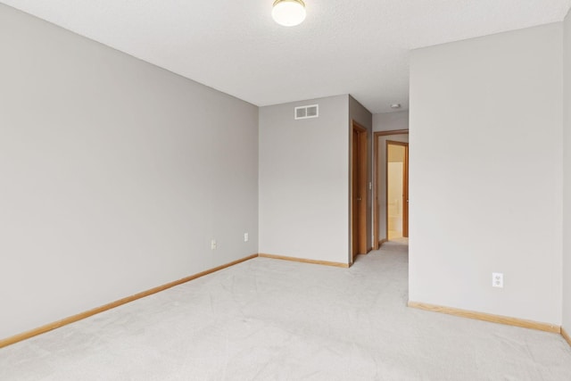 unfurnished room featuring light colored carpet and a textured ceiling