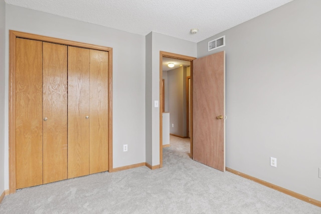 unfurnished bedroom featuring a closet, light colored carpet, and a textured ceiling