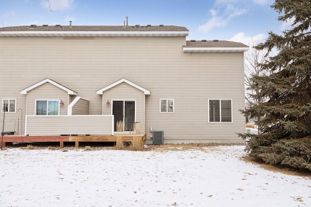 snow covered rear of property with a wooden deck and cooling unit