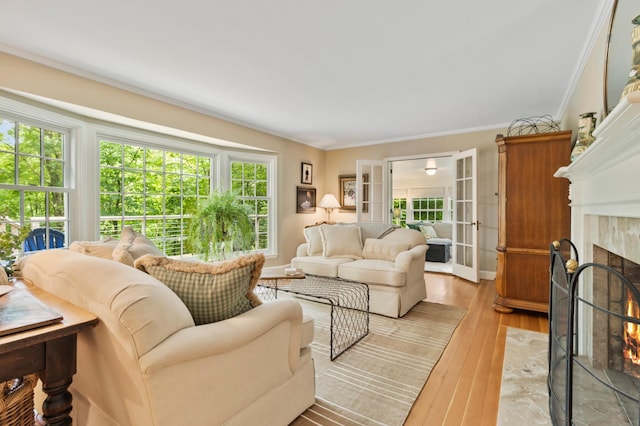 living room with a premium fireplace, crown molding, light hardwood / wood-style floors, and french doors