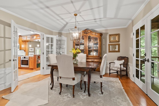 dining space with ornamental molding, light hardwood / wood-style flooring, french doors, and a chandelier