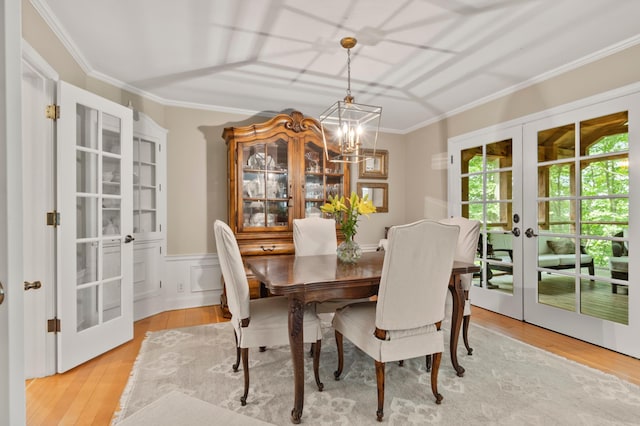 dining space featuring french doors, an inviting chandelier, ornamental molding, and light hardwood / wood-style flooring